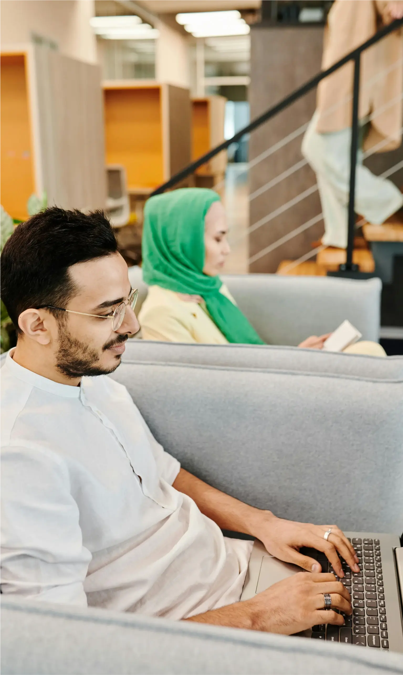 Man and woman sitting in chairs working on laptops