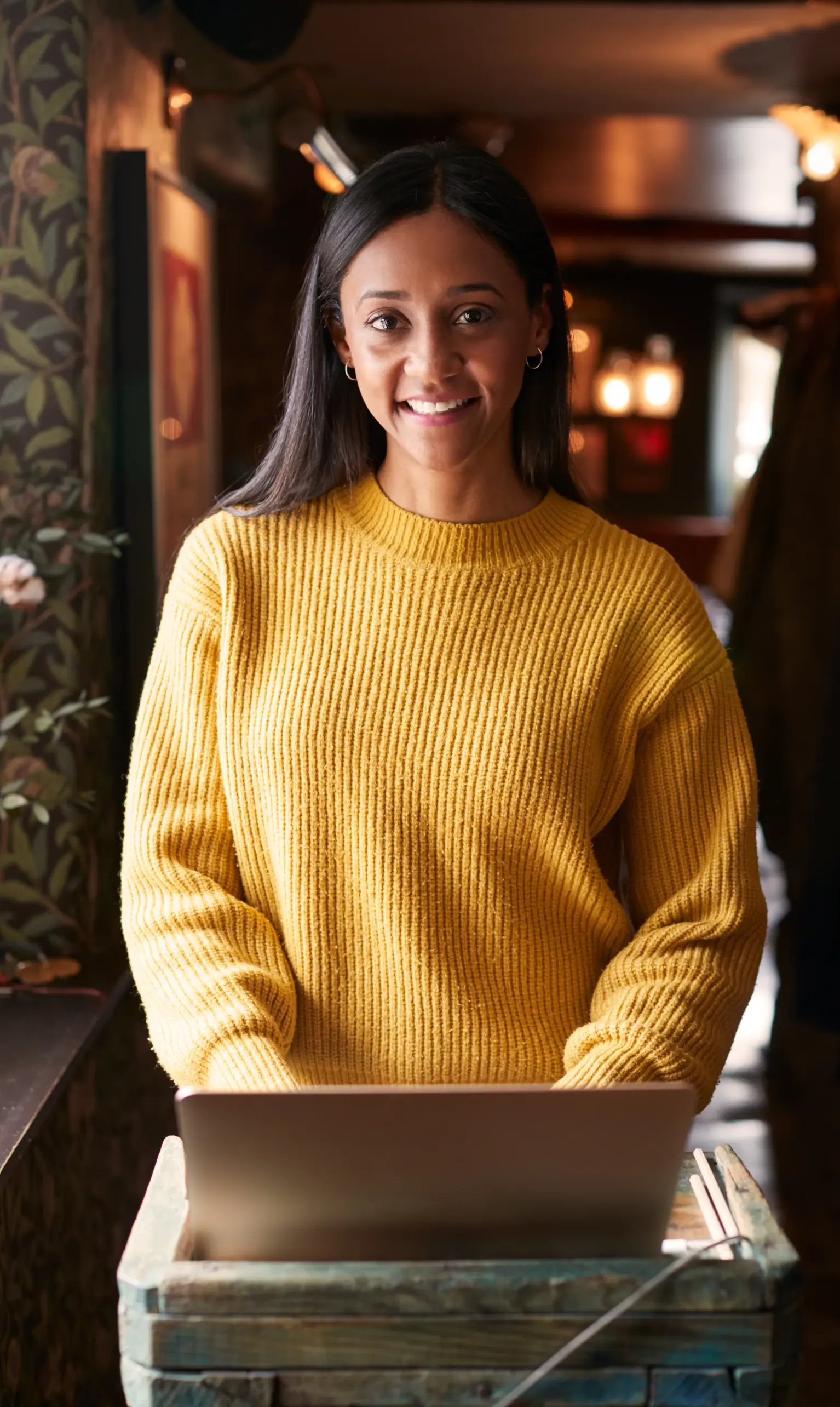 Portrait Of Female Receptionist Working On Laptop At Hotel Check In