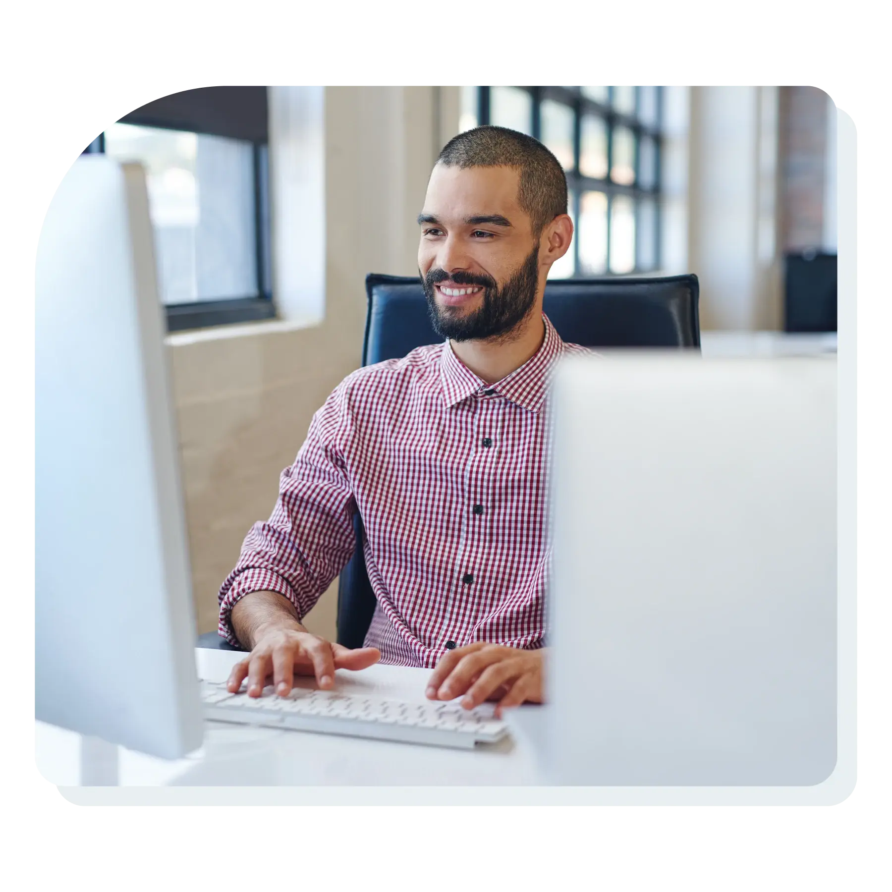 man_sitting_at_computer_smiling_while_looking_at_screen